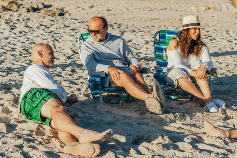 a group of people sitting on top of a sandy beach, sitting down, older male, profile image, fan favorite