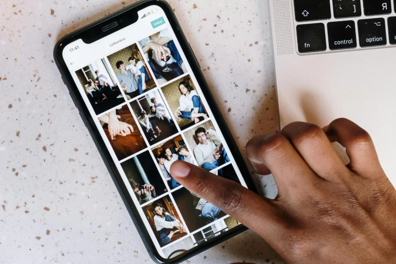 a person holding a cell phone next to a laptop, a picture, trending on pexels, process art, photos of family on wall, teal aesthetic, thumbnail, album photo