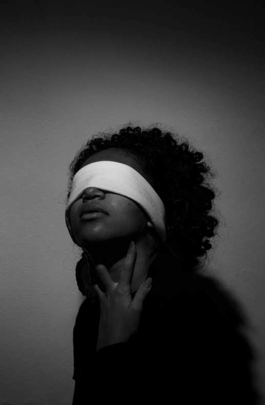 a woman with a blindfold on her face, a black and white photo, inspired by Carrie Mae Weems, unsplash, open eye freedom, african american girl, injured, alternate album cover