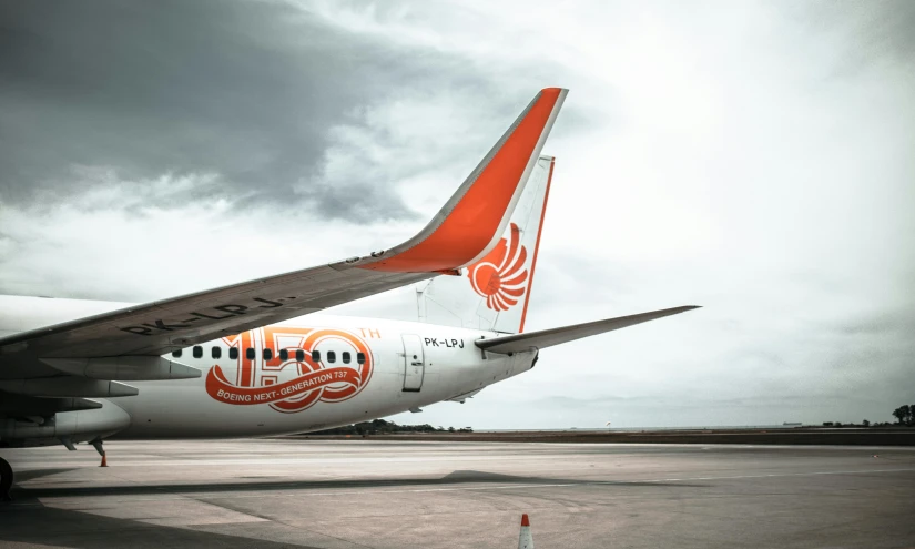 a large jetliner sitting on top of an airport tarmac, pexels contest winner, lyco art, orange and white color scheme, dragon tail, indonesia, side profile artwork