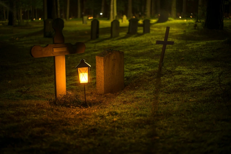 a cemetery with tombstones and crosses lit up at night, pexels, lantern light besides, raking light, lantern, distant photo