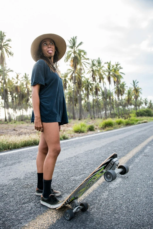 a woman standing next to a skateboard on a road, bali, profile image, black, kano)