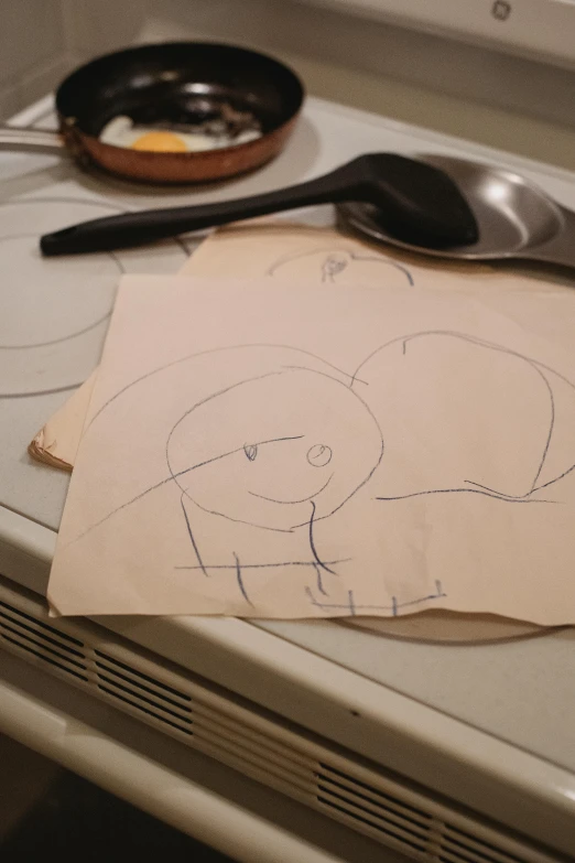 a piece of paper sitting on top of a stove, a child's drawing, reddit, process art, low quality photo, eating, ilustration, face line drawing