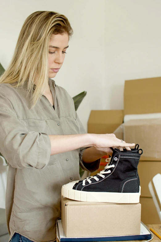 a woman putting a shoe on top of a box, trending on pexels, process art, portrait of tall, label, black canvas, thumbnail