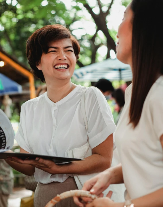 a couple of women standing next to each other, trending on unsplash, happening, carrying a tray, welcoming grin, restaurant menu photo, south east asian with round face