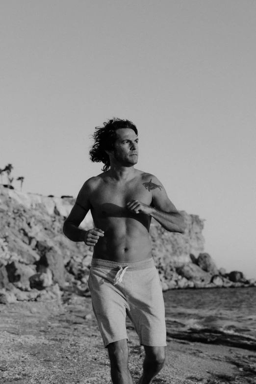 a black and white photo of a man running on the beach, by Alexis Grimou, happening, frank dillane, lean man with light tan skin, in white clothes, michal