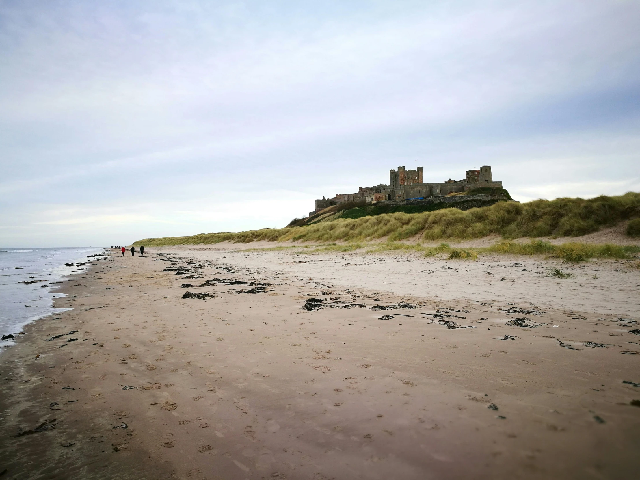 a castle sitting on top of a sandy beach, by Andrew Robertson, unsplash, renaissance, people walking around, 2 0 0 0's photo