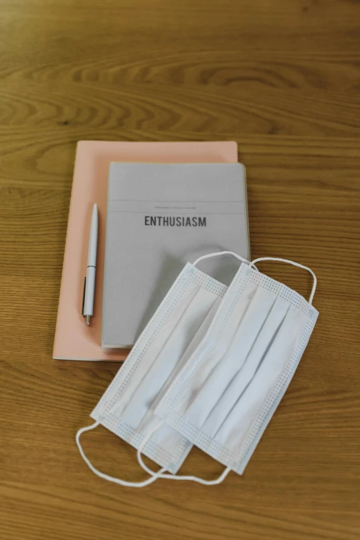 a book sitting on top of a wooden table next to a face mask, holding notebook, thumbnail, embossed, enjoyable