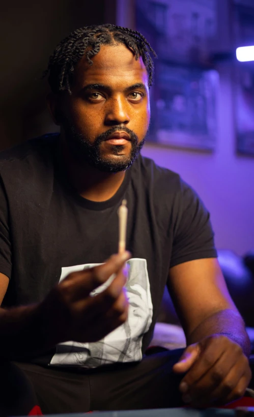 a man sitting at a table with a cigarette in his hand, a portrait, featured on reddit, kayne west, promotional image, profile image, thumbnail