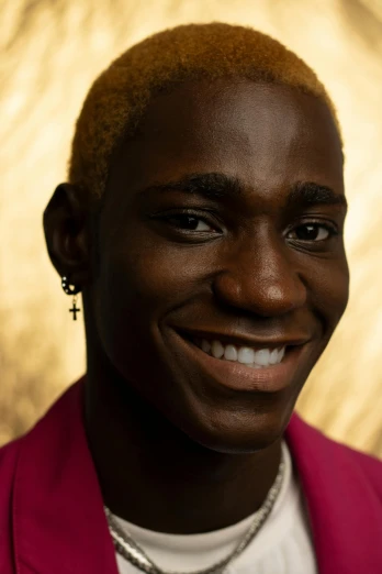 a close up of a person wearing a pink jacket, by Ellen Gallagher, adut akech, smiling male, gold hair, non binary model