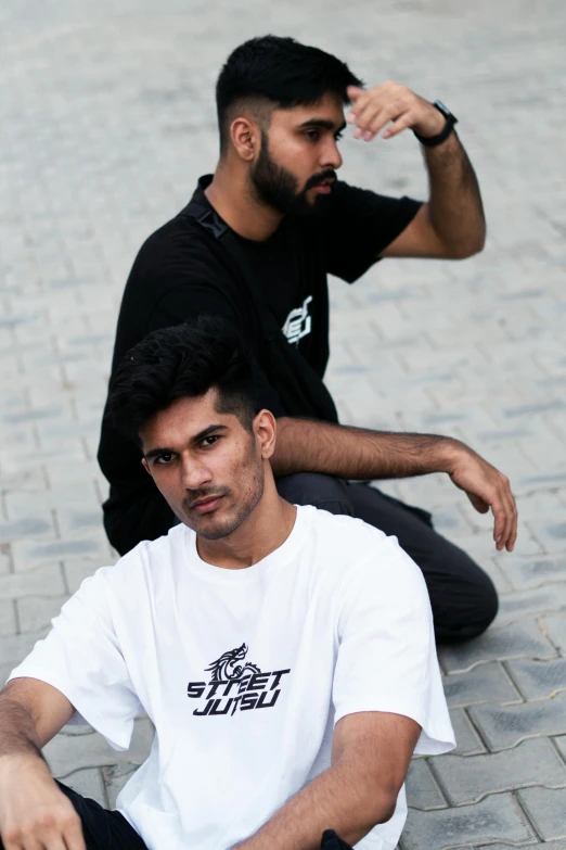 two men sitting on the ground with skateboards, a portrait, trending on unsplash, hurufiyya, tshirt, middle eastern, looking serious, white and black