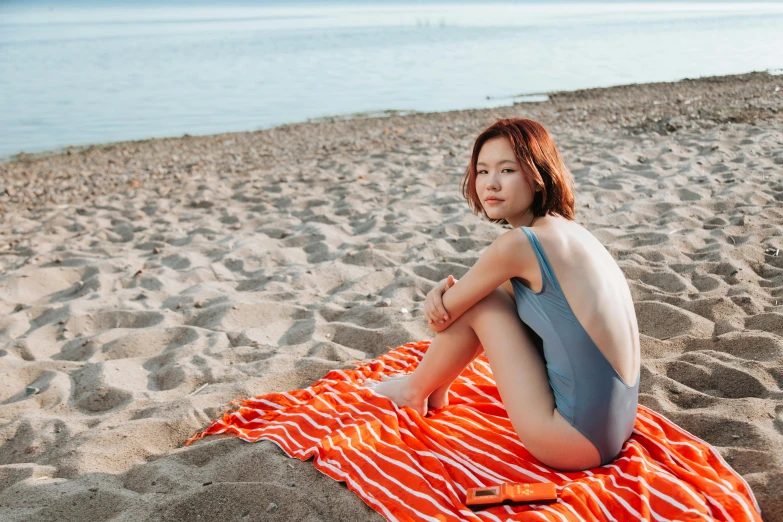 a woman sitting on a towel on a beach, pexels contest winner, jung jaehyun, orange skin, one piece style, youtube thumbnail