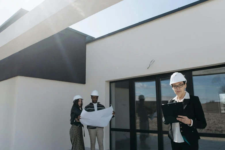 a woman in a hard hat standing in front of a building, people looking at a house, looking at the ceiling, white wall complex, lachlan bailey