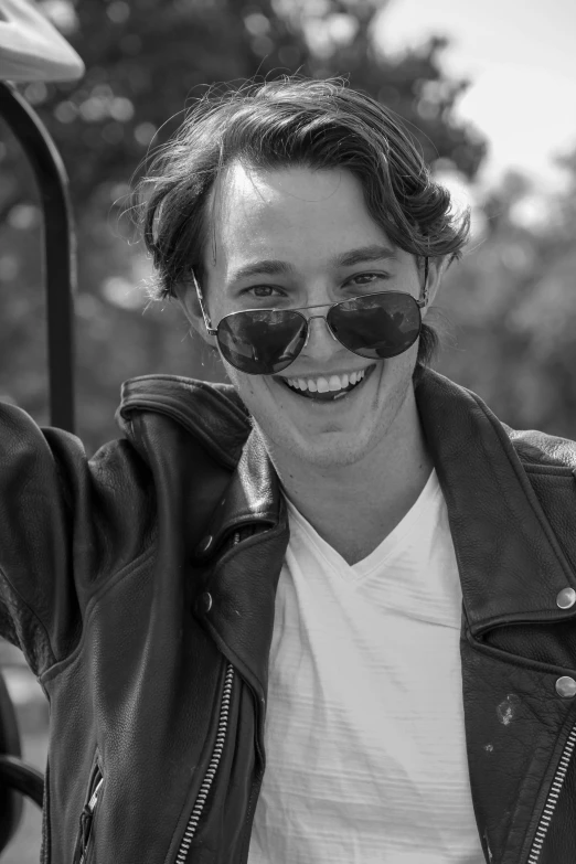 a black and white photo of a woman in a leather jacket, unsplash, photorealism, smiling male, teenage jughead jones, with sunglasses, flume