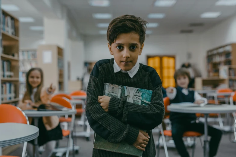 a young boy standing in a library holding a book, an album cover, pexels contest winner, danube school, cinematic film still, in a school classroom, amr elshamy, all looking at camera