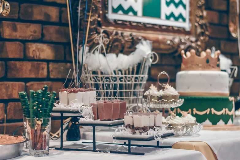 a table topped with cakes and desserts next to a brick wall, by Emma Andijewska, unsplash, happening, old hollywood themed, white, holiday, indoor picture