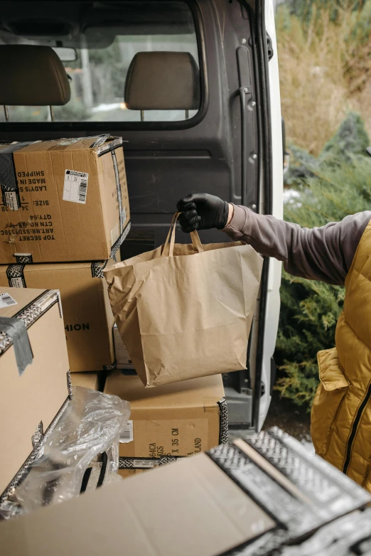 a man standing next to a van filled with boxes, pexels, renaissance, holding a gold bag, ecommerce photograph, thumbnail, gloves on hands