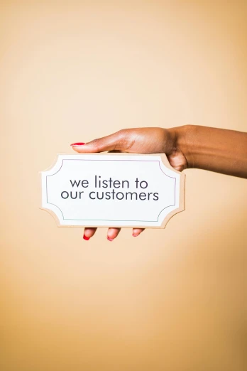 a woman holding a sign that says we listen to our customers, an album cover, by Arabella Rankin, trending on unsplash, private press, made of glazed, sustainable materials, porcelain, brown