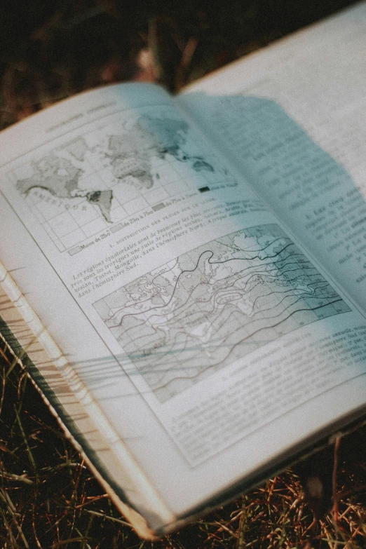 an open book sitting on the ground, an etching, pexels, analytical art, map cartography, barometric projection, wet climate, science journal cover