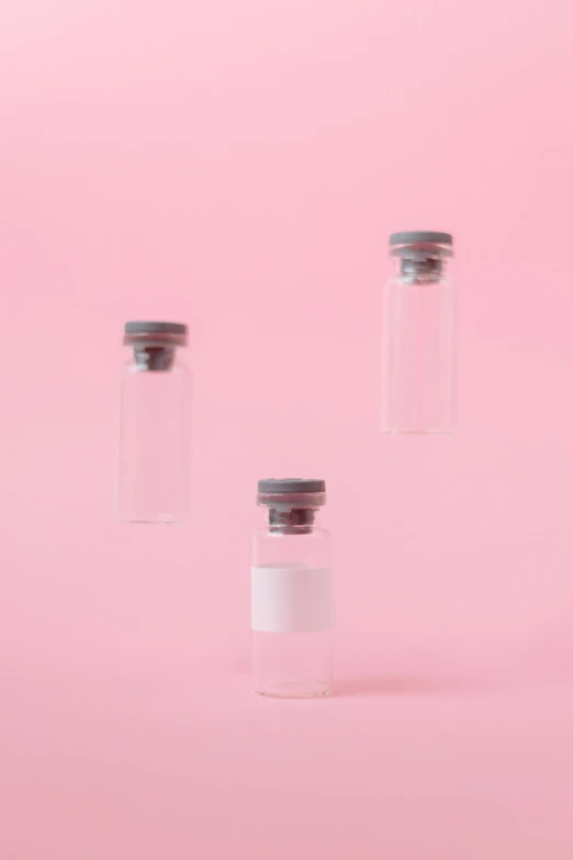 three empty glass vials on a pink background, trending on pexels, augments, miniatures, yasumoto oka, medical labels