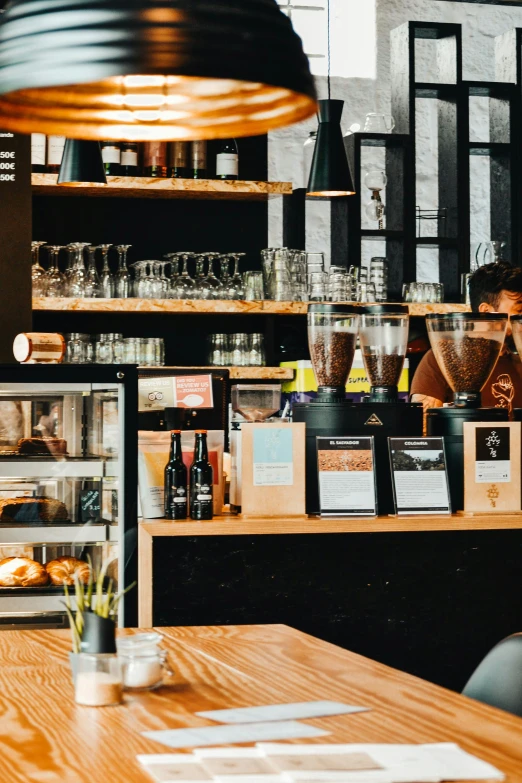 a person sitting at a table in a restaurant, by Niko Henrichon, trending on unsplash, large sweet jars on shelves, coffee machine, panoramic shot, aussie baristas