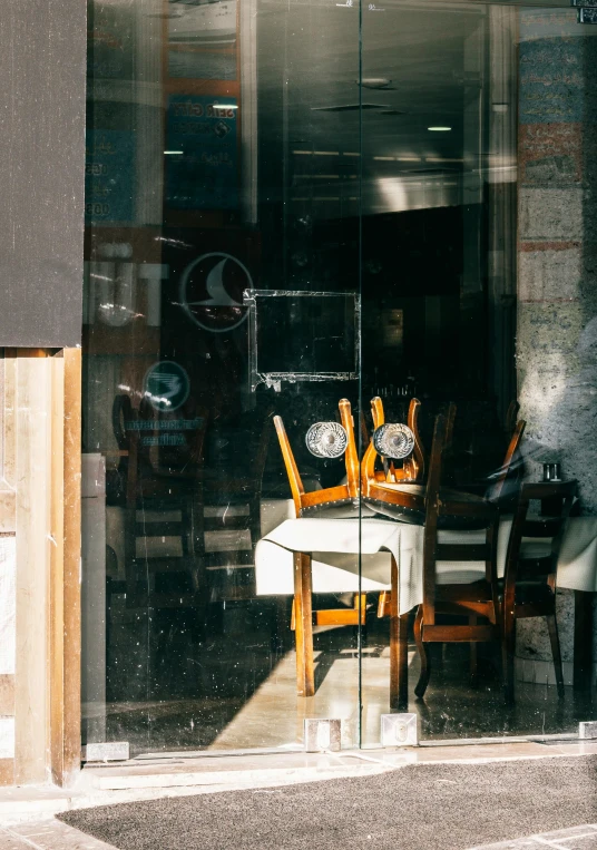 a person sitting at a table outside of a restaurant, by Niko Henrichon, trending on unsplash, modernism, nesting glass doors, seen through broken glass, thumbnail, brown