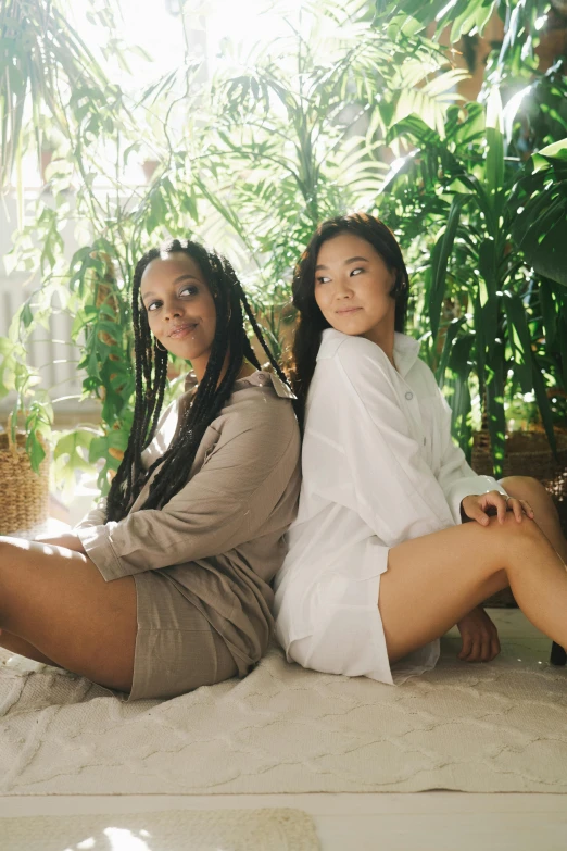 a couple of women sitting on top of a bed, an album cover, by Jessie Alexandra Dick, unsplash, greenery, diverse outfits, wearing a white button up shirt, thighs