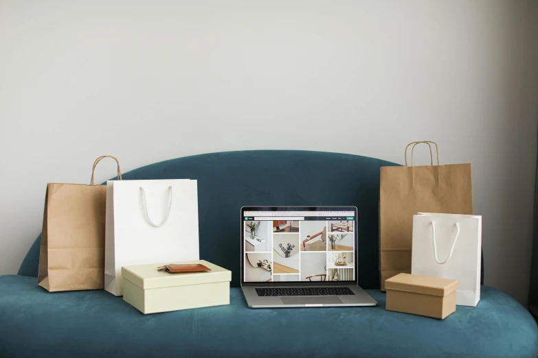 a laptop computer sitting on top of a blue couch, by Everett Warner, trending on pexels, visual art, birthday wrapped presents, shop front, bags on ground, sea - green and white clothes