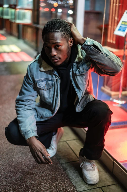 a man squatting in front of a store window, an album cover, trending on pexels, wearing a turtleneck and jacket, thancred waters, posing in an urban street, good lighted photo