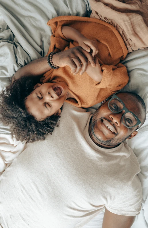 a group of people laying on top of a bed, fatherly, portrait featured on unsplash, brown skinned, portrait of two people