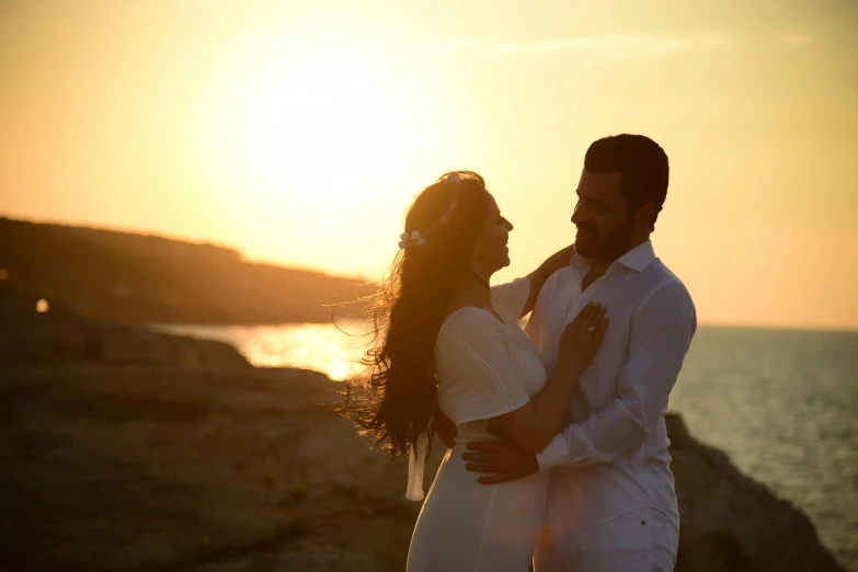 a man and a woman standing next to each other, by Dan Luvisi, pexels contest winner, romanticism, cyprus, sun behind her, youtube thumbnail, happy couple
