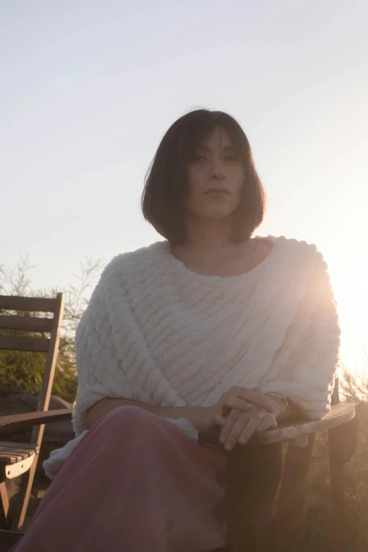 a woman sitting on top of a wooden bench, an album cover, white french bob, at golden hour, looking serious, ( ( theatrical ) )