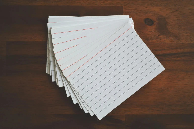 a stack of lined paper sitting on top of a wooden table, pexels, cards, thin red lines, multiple stories, whiteboards