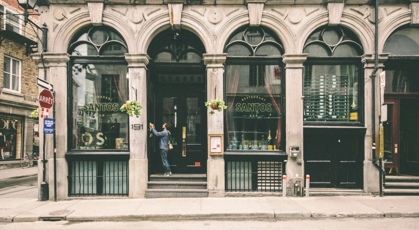 a man standing in the doorway of a building, by Dennis Flanders, pexels contest winner, art nouveau, restaurant exterior photography, montreal, a quaint, parce sepulto