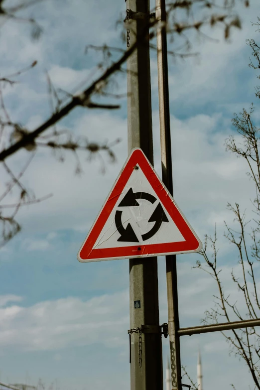 a close up of a street sign on a pole, by Adam Marczyński, unsplash, precisionism, triangle inside circle, waste, whirling, three