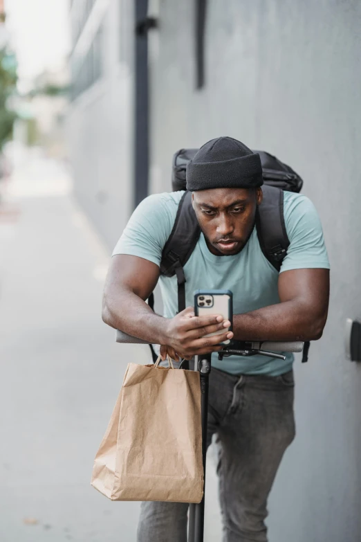 a man on a scooter looking at his cell phone, trending on pexels, renaissance, with a backpack, offering a plate of food, black man, a muscular