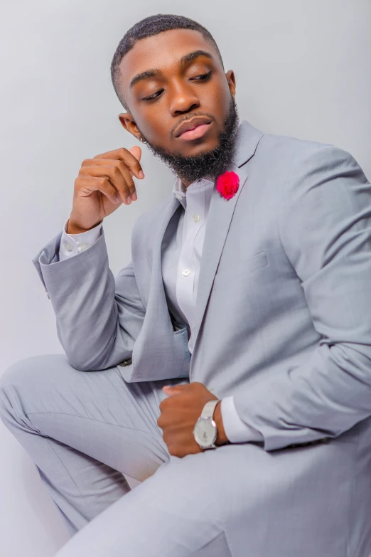 a man in a suit sitting on a chair, an album cover, by Chinwe Chukwuogo-Roy, trending on pexels, casual pose, grey suit, pastel', elegant glamor pose