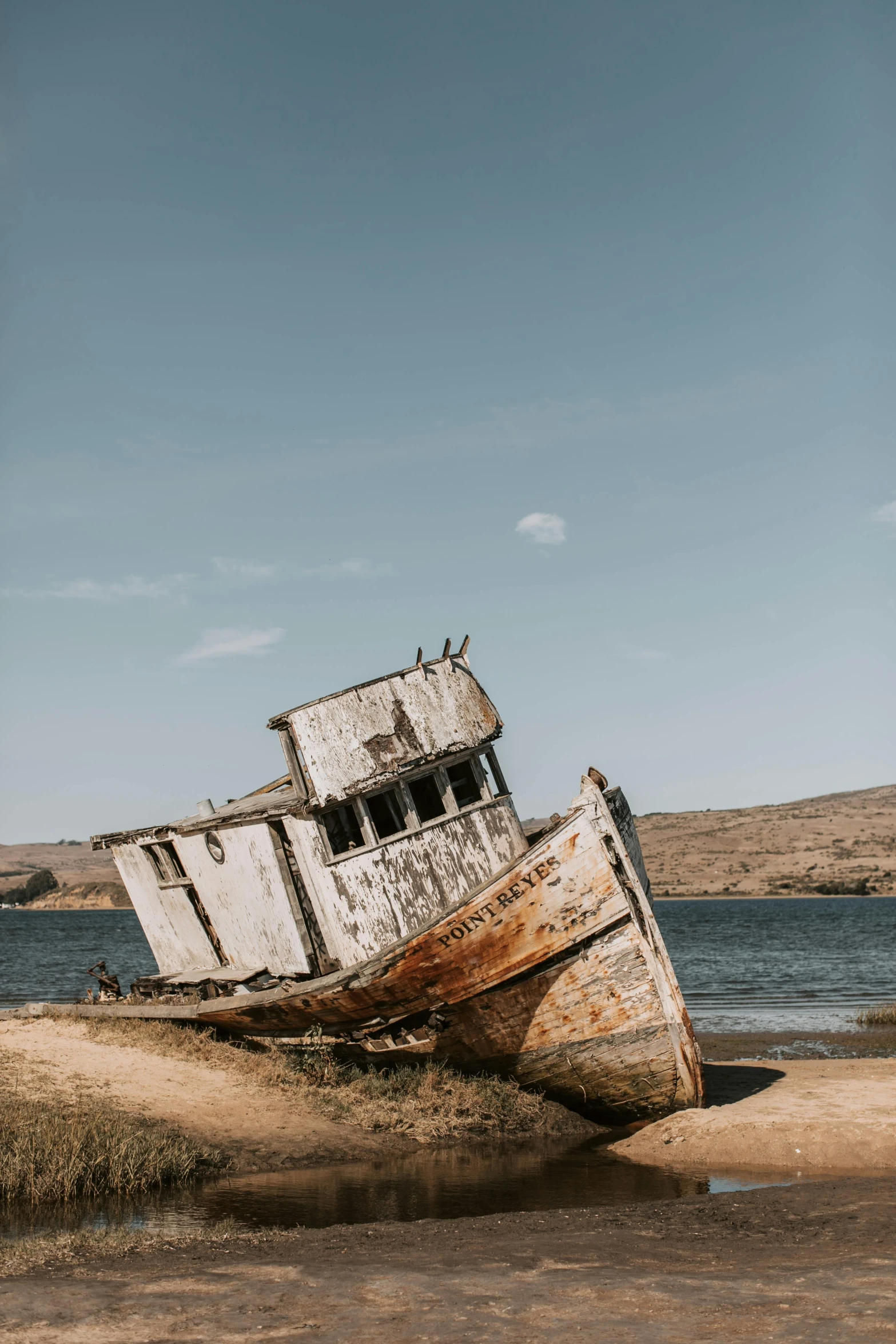 a boat sitting on top of a sandy beach, unsplash contest winner, post apocalyptic san francisco, with damaged rusty arms, exterior, ship on lake
