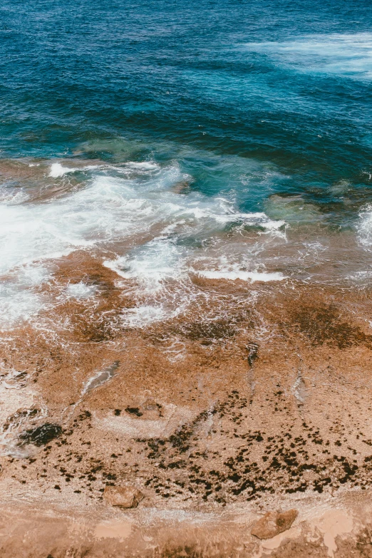 a man riding a surfboard on top of a sandy beach, an album cover, trending on unsplash, oil spill, wide aerial shot, reefs, puerto rico