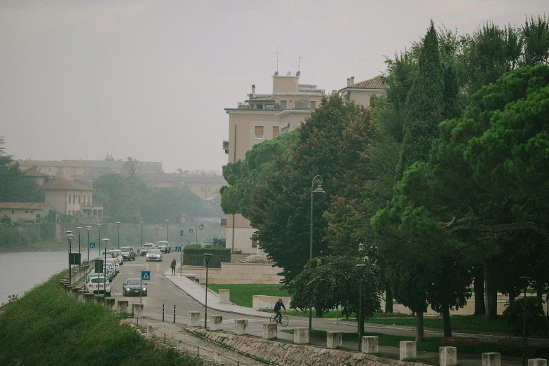 a street filled with lots of traffic next to a river, a picture, unsplash contest winner, renaissance, alvaro siza, slight haze, from italica, in a city park