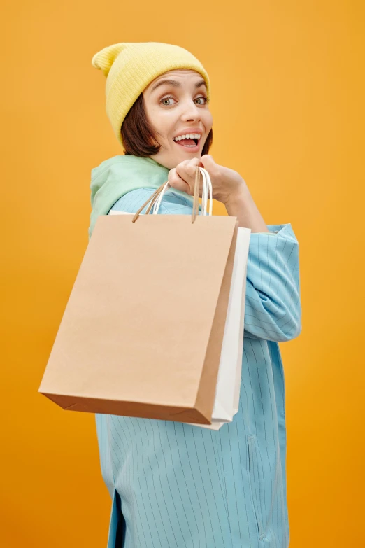 a woman holding shopping bags and talking on the phone, shutterstock contest winner, minimalism, yellow clothes, baggy clothing and hat, thumbnail, brown