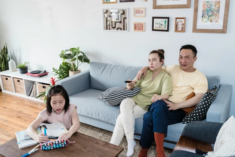 a man and woman sitting on a couch in a living room, inspired by Eddie Mendoza, pexels contest winner, incoherents, portrait of family of three, keng lye, playing games, film still promotional image