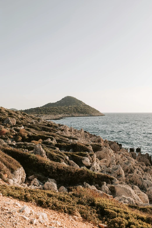 a man standing on top of a rocky beach next to the ocean, les nabis, pyramid surrounded with greenery, pathos, minimalist, 2019 trending photo