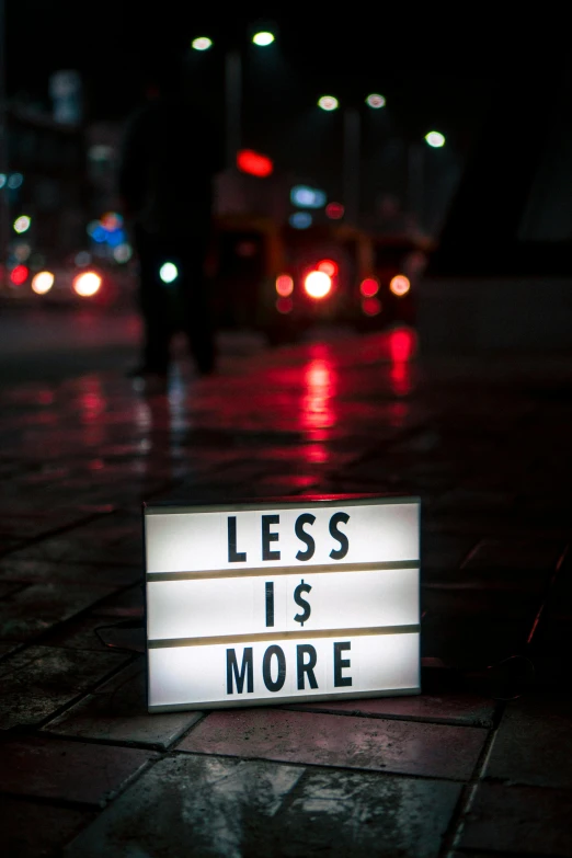 a sign that says less is more on the sidewalk, an album cover, by Alexis Grimou, unsplash, light show, 256435456k film, trash, f/3.2