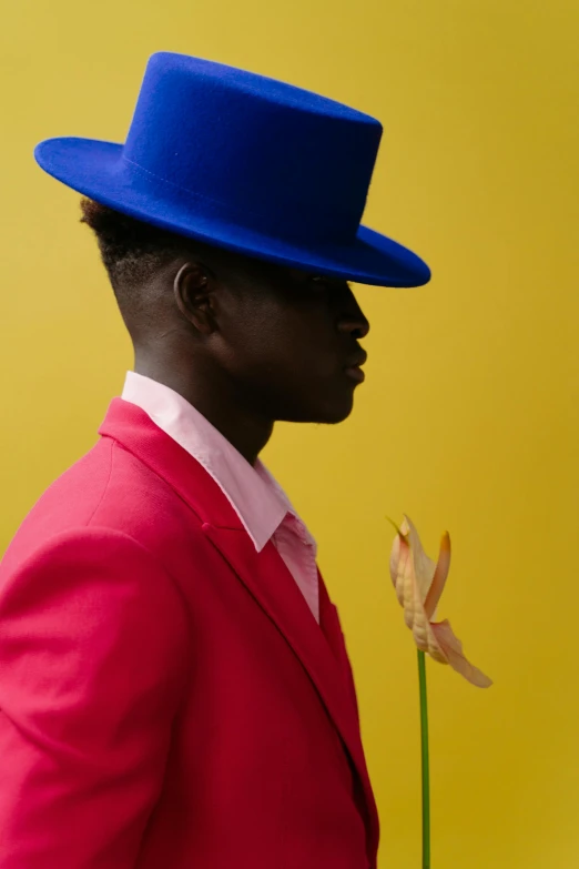 a man in a red suit and a blue hat, an album cover, pexels contest winner, adut akech, lgbtq, flowers, profile shot