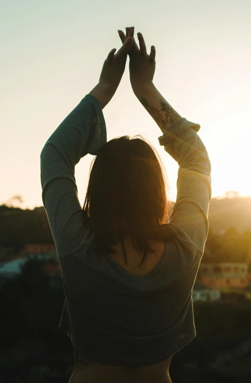 a woman standing on top of a hill with her hands in the air, pexels contest winner, arched back, meditation, standing on a rooftop, softly lit