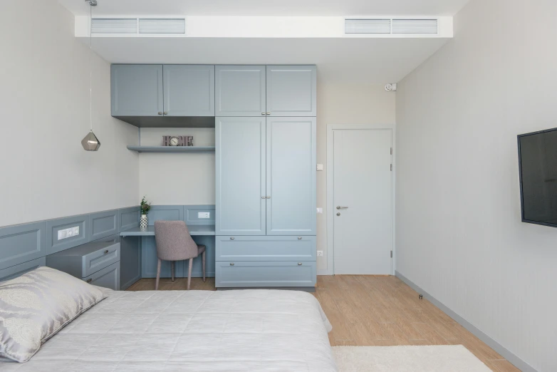 a bed room with a neatly made bed and a flat screen tv, inspired by Reinier Nooms, unsplash, pastel blue, cabinets, ameera al taweel, profile image