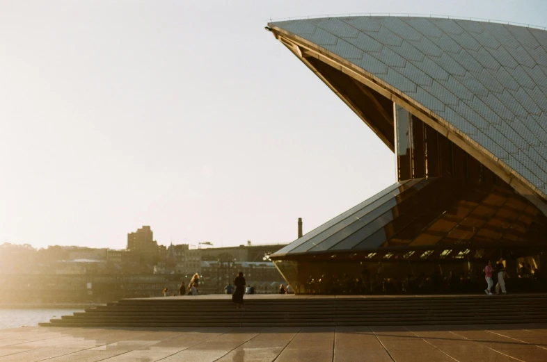 a group of people standing in front of a building, a picture, inspired by Sydney Carline, pexels contest winner, khedival opera house, golden morning light, norman foster, seen from outside