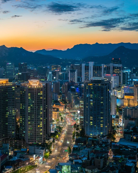 a view of a city at night with mountains in the background, south korean male, blog-photo