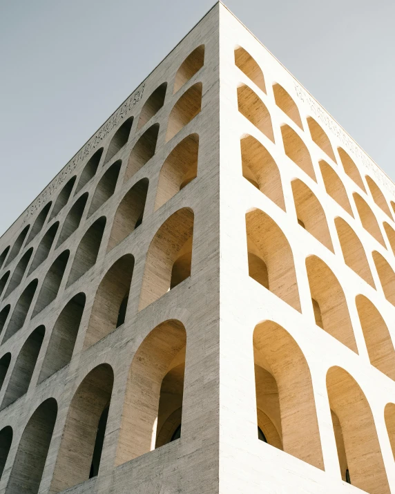 a tall building with arches on the side of it, inspired by Ricardo Bofill, unsplash contest winner, cinder blocks, italian renaissance architecture, golden curve structure, many holes